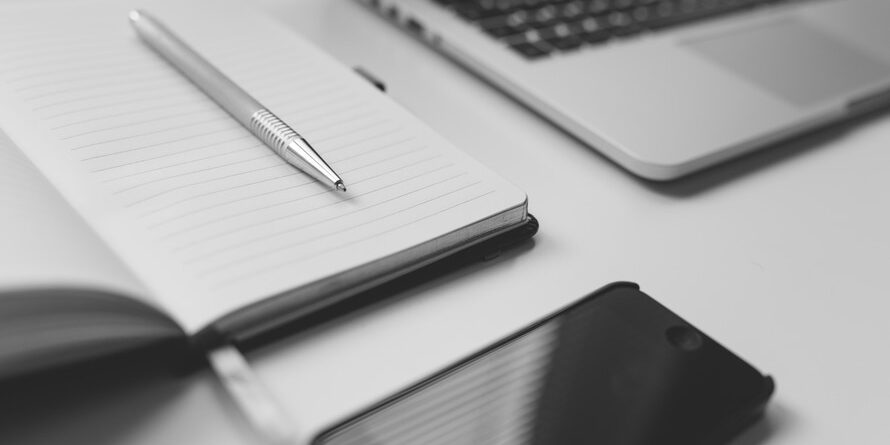 Writing Close up of desk with laptop, mobile, notebook and paper