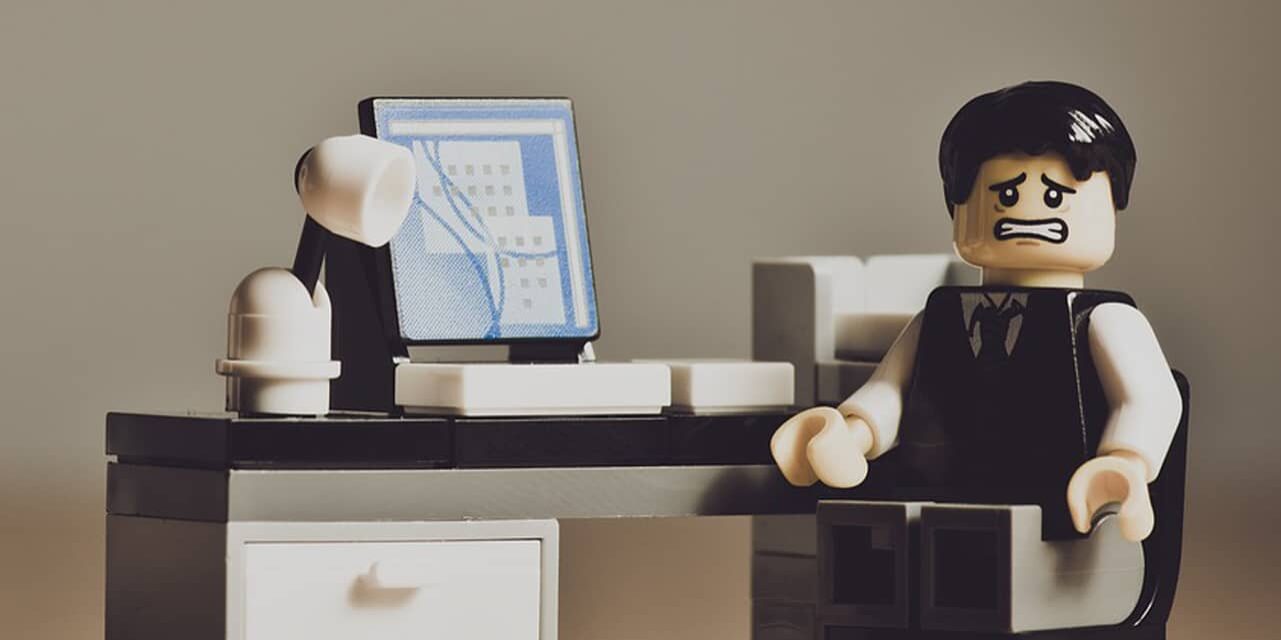 despaired_sq Lego style figure at a desk looking stressed and worried